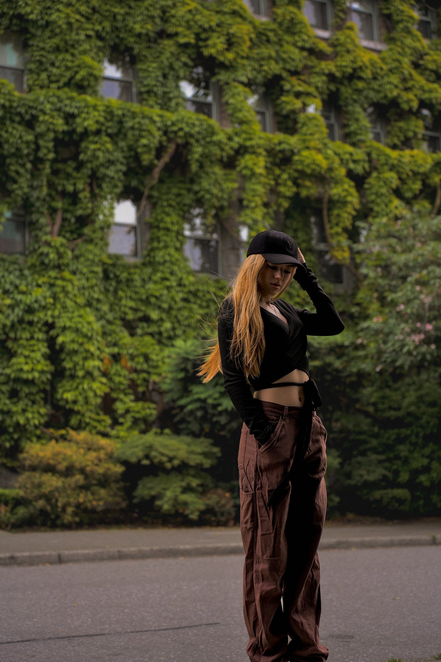 Female model standing in front of a moss covered building wearing the Elation buckle hat from Vancouver Signature