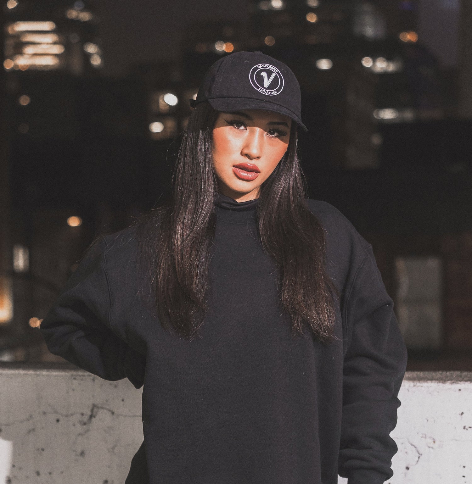 Female model wearing the black and white Elation relaxed-fit hat by Vancouver Signature at night