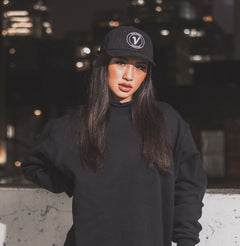 Female model wearing the black and white Elation relaxed-fit hat by Vancouver Signature at night