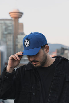 Close-up of a male model wearing the royal and black First-Up lifestyle hat outdoors