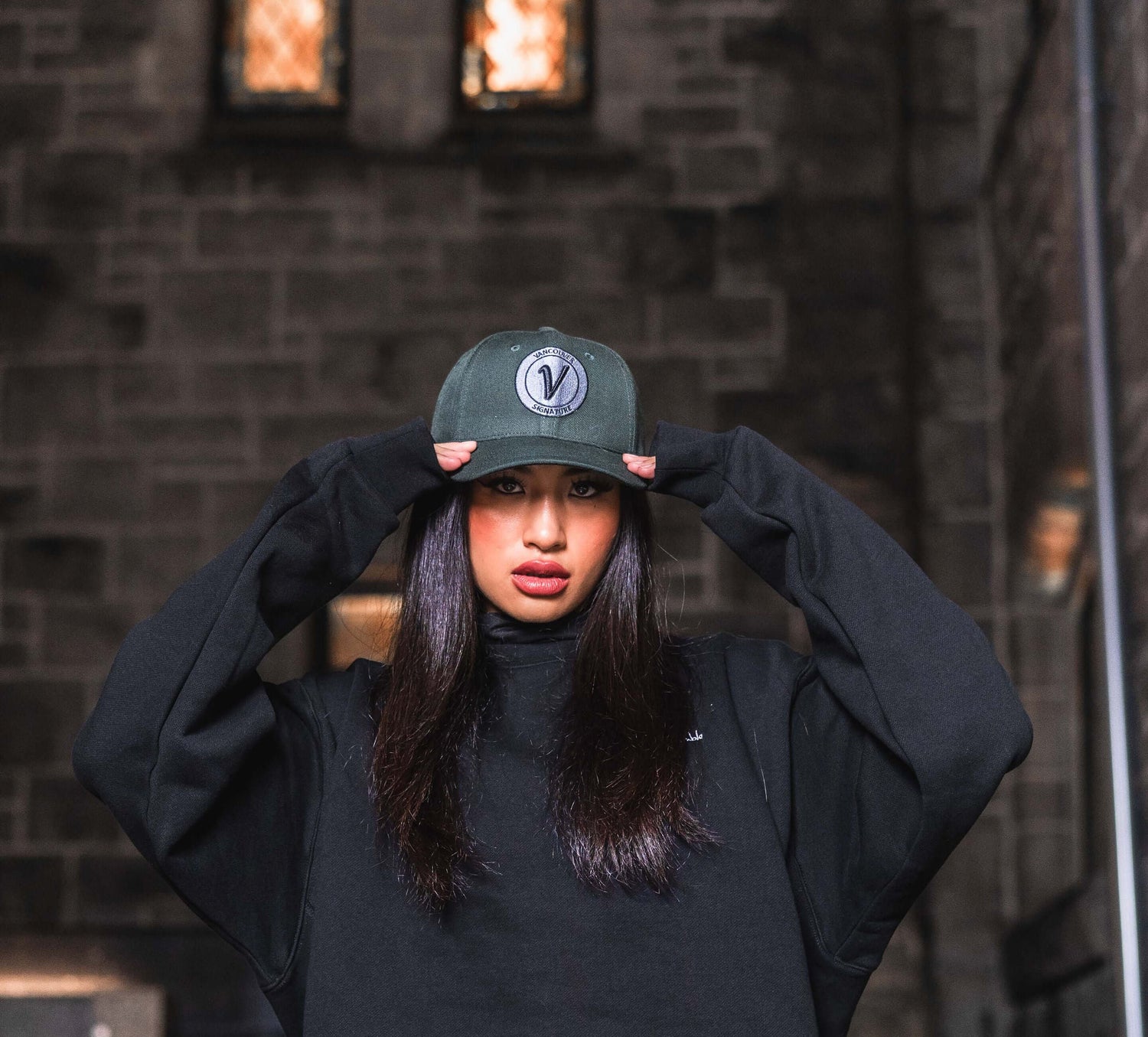 Woman wearing Vancouver Signature Listo structured hat against a dark urban backdrop