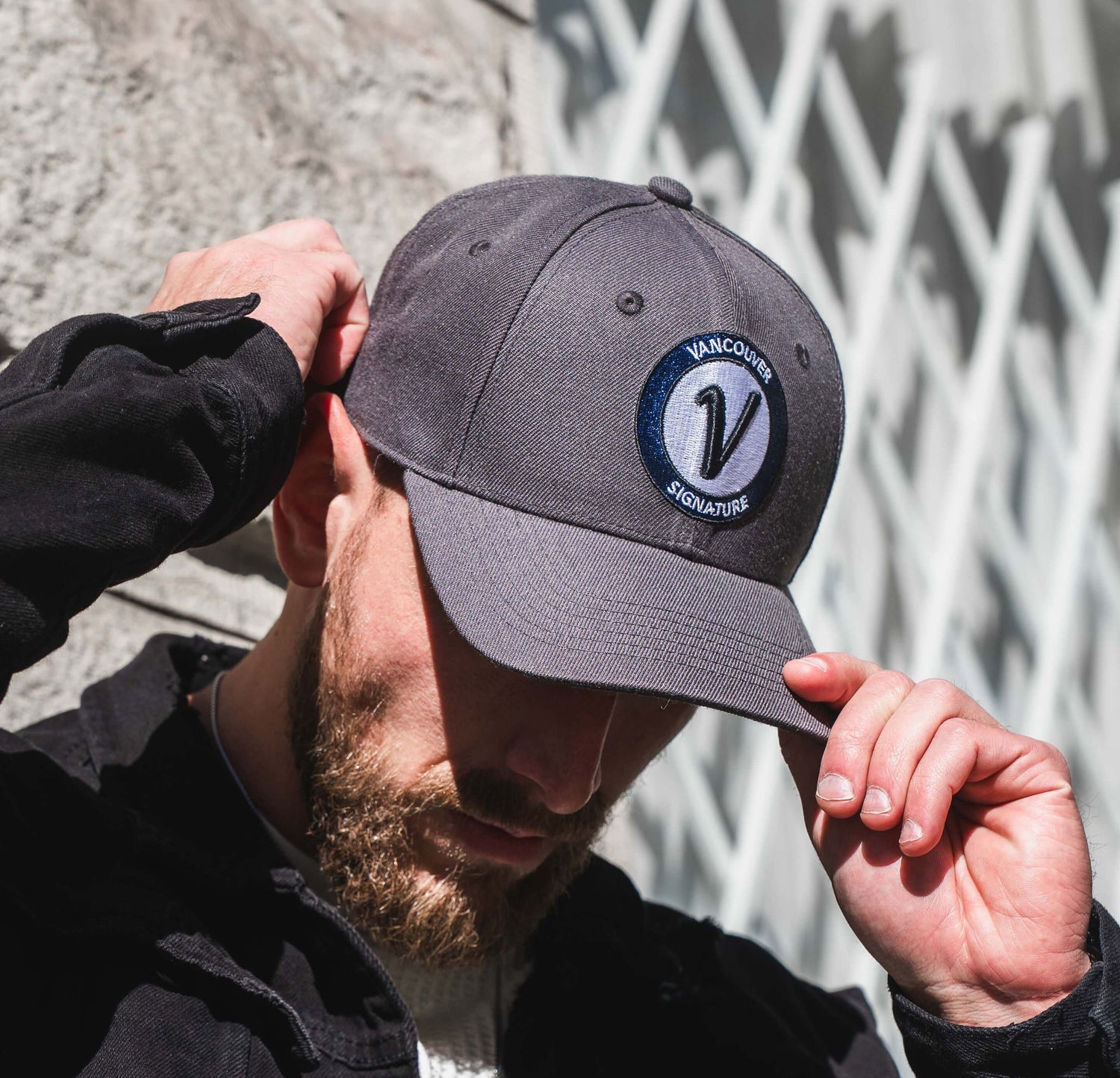 Man wearing stone and black Vancouver Signature Listo structured hat outdoors